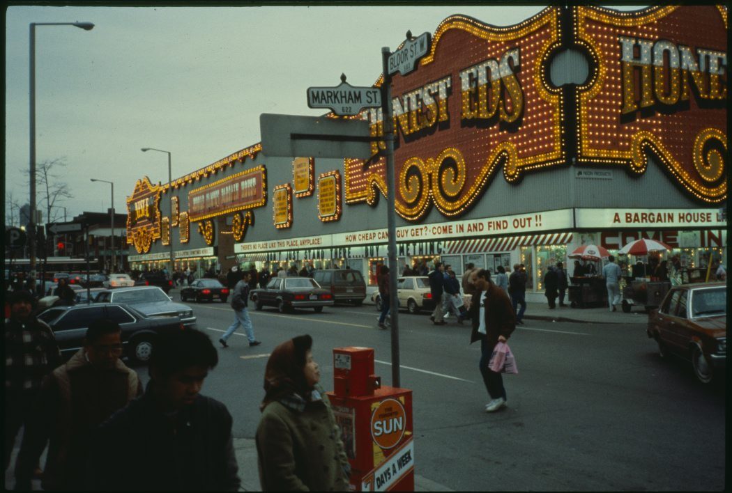 Bloor street view of Honest Ed's department store. The sign is bright orange and in a circus style.
